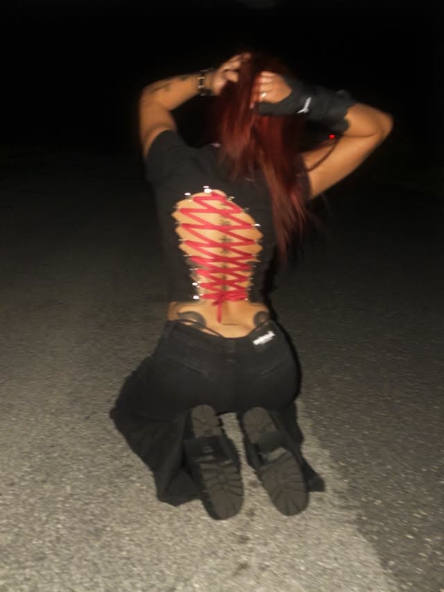 Lyla from behind at night, a lace-up detail over a black top
