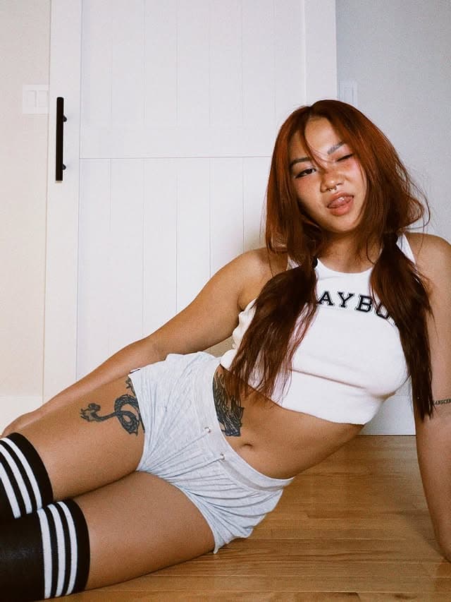 Lyla lounging on the floor in a white graphic tank and shorts